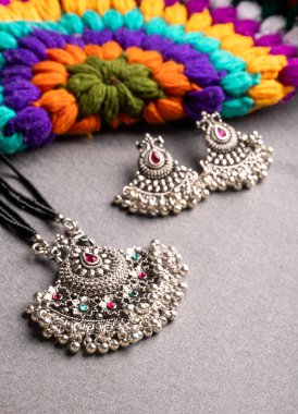 Hint geleneksel antikası ya da renkli örgü arka planda küpeleri olan retro tarzı kolye.