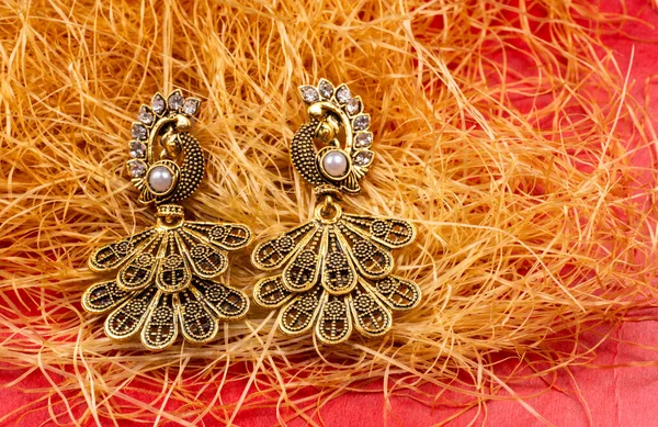 Beautiful earrings with corn plant on red background