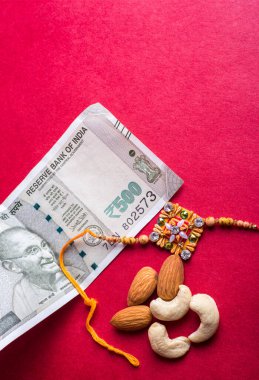 Traditional Indian jewelry with peanuts and money banknotes on red background