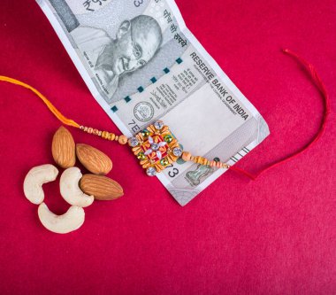 Traditional Indian jewelry with peanuts and money banknotes on red background