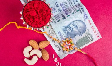 Traditional Indian jewelry with rice, spice, peanuts and money banknotes on red background