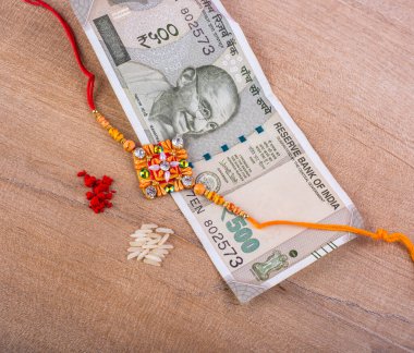 Traditional Indian jewelry with rice, spice and money banknotes on wooden background