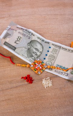 Traditional Indian jewelry with rice, spice and money banknotes on wooden background