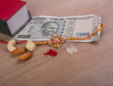 Traditional Indian jewelry with rice, spice, peanuts, box and money banknotes on wooden background