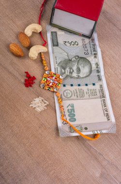 Traditional Indian jewelry with rice, spice, peanuts, box and money banknotes on wooden background