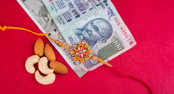 Traditional Indian jewelry with peanuts and money banknotes on red background