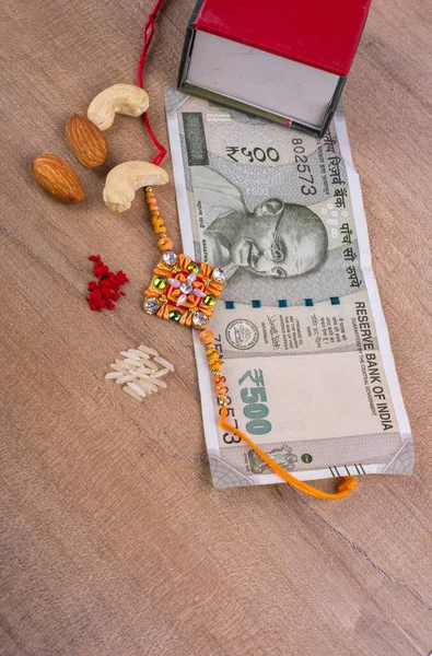 Traditional Indian jewelry with rice, spice, peanuts, box and money banknotes on wooden background