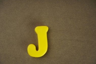 Letter J isolated on brown background