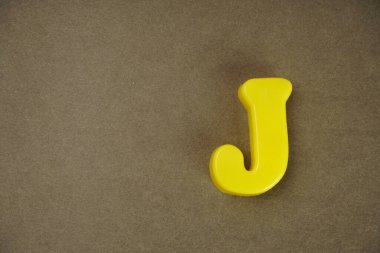 Letter J isolated on brown background