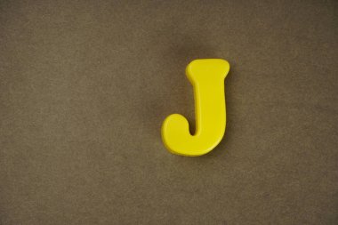 Letter J isolated on brown background