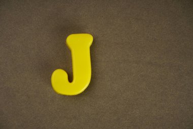 Letter J isolated on brown background