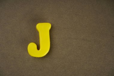 Letter J isolated on brown background