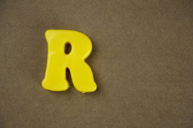 Letter R isolated on brown background
