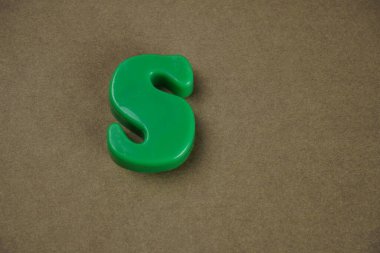 Letter S isolated on brown background 