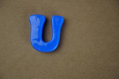 Letter U isolated on brown background