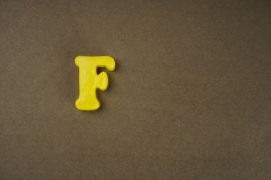 Letter F isolated on brown background
