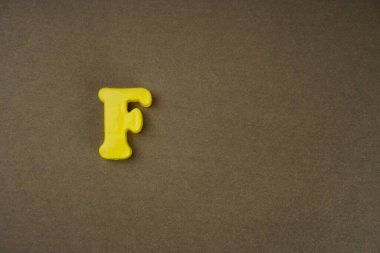 Letter F isolated on brown background