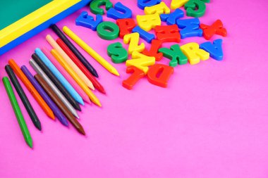 English alphabet letters, colorful pencils and childish school blackboard on pink background. Back to school. Education concept