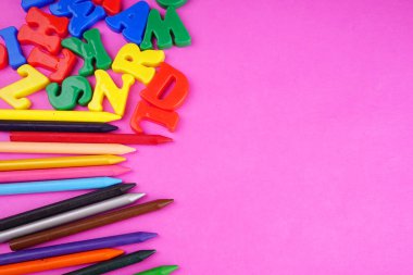 English alphabet letters and colorful pencils on pink background. Back to school. Education concept 