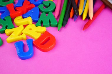 English alphabet letters and colorful pencils on pink background. Back to school. Education concept 