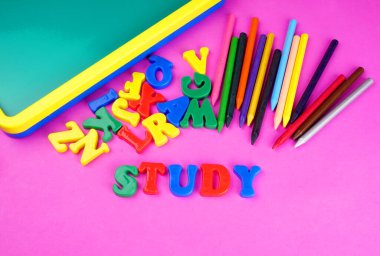 English alphabet letters, colorful pencils and childish school blackboard on pink background. Back to school. Education concept