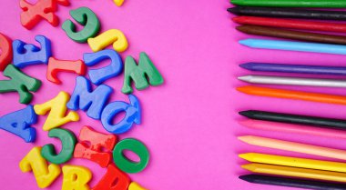 English alphabet letters and colorful pencils on pink background