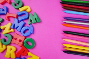 English alphabet letters and colorful pencils on pink background