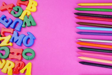 English alphabet letters and colorful pencils on pink background