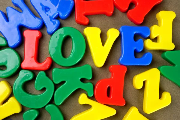 Colorful English alphabet with word 'Love' on brown background