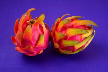 Fresh ripe dragon fruit on purple background