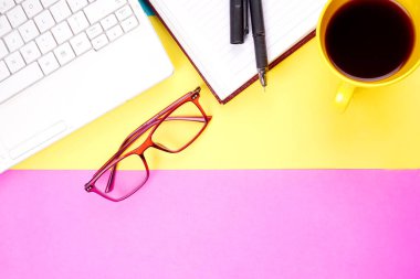 Glasses, smartphone, notebook, pencil and coffee cup on colorful background