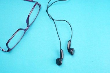 Glasses and headphones on turquoise background