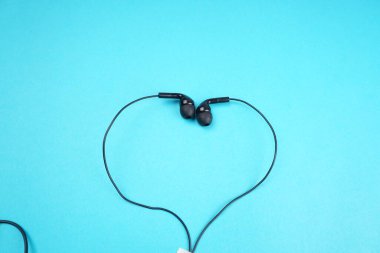 Headphones in form of heart on turquoise background