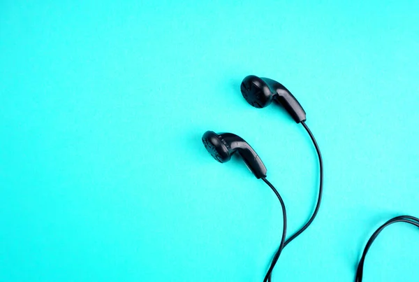 Black headphones on turquoise background