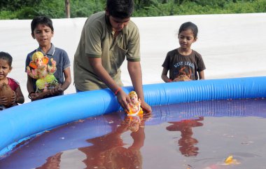 People bathing Hindu statue at traditional religious holiday in India