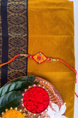 Indian Festival: Rakhi with rice grains, kumkum, sweets and haldi on plate with an elegant Rakhi. A traditional Indian wrist band which is a symbol of love between Brothers and Sisters