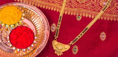 Mangalsutra or Golden Necklace to wear by a married hindu women, arranged with traditional saree with haldi, kumkum and grain rice on plate. Indian Traditional Jewellery.