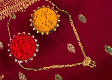 Mangalsutra or Golden Necklace to wear by a married hindu women, arranged with traditional saree with haldi, kumkum and grain rice on plate. Indian Traditional Jewellery.