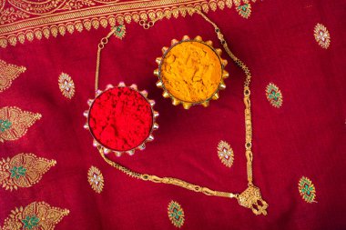 Mangalsutra or Golden Necklace to wear by a married hindu women, arranged with traditional saree with haldi, kumkum and grain rice on plate. Indian Traditional Jewellery.