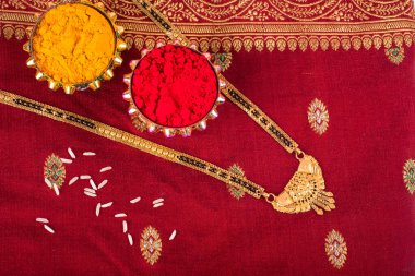 Mangalsutra or Golden Necklace to wear by a married hindu women, arranged with traditional saree with haldi, kumkum and grain rice on plate. Indian Traditional Jewellery.