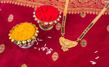 Mangalsutra or Golden Necklace to wear by a married hindu women, arranged with traditional saree with haldi, kumkum and grain rice on plate. Indian Traditional Jewellery.