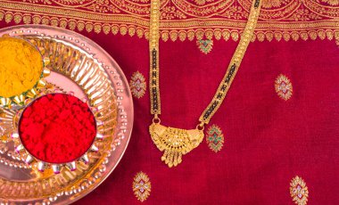 Mangalsutra or Golden Necklace to wear by a married hindu women, arranged with traditional saree with haldi, kumkum and grain rice on plate. Indian Traditional Jewellery.