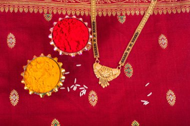 Mangalsutra or Golden Necklace to wear by a married hindu women, arranged with traditional saree with haldi, kumkum and grain rice on plate. Indian Traditional Jewellery.