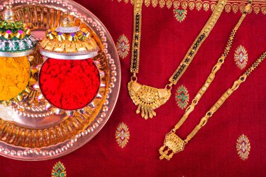 Mangalsutra or Golden Necklace to wear by a married hindu women, arranged with traditional saree with haldi, kumkum and grain rice on plate. Indian Traditional Jewellery.