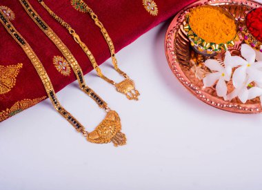 Mangalsutra or Golden Necklace to wear by a married hindu women, arranged with traditional saree with haldi, kumkum and flowers on plate