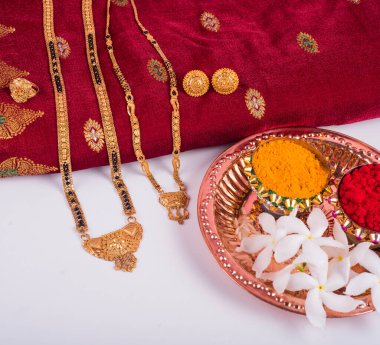 Mangalsutra or Golden Necklace to wear by a married hindu women, arranged with traditional saree with haldi, kumkum and flowers on plate