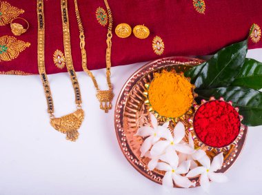 Mangalsutra or Golden Necklace to wear by a married hindu women, arranged with traditional saree with haldi, kumkum and flowers on plate