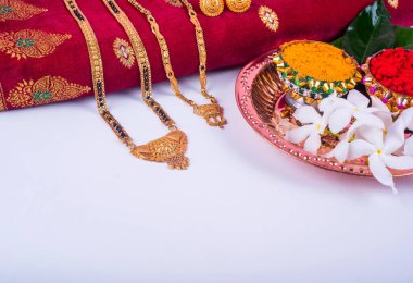 Mangalsutra or Golden Necklace to wear by a married hindu women, arranged with traditional saree with haldi, kumkum and flowers on plate