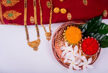 Mangalsutra or Golden Necklace to wear by a married hindu women, arranged with traditional saree with haldi, kumkum and flowers on plate