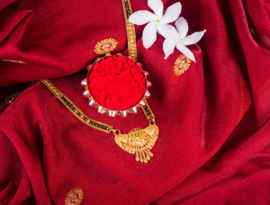 Mangalsutra or Golden Necklace to wear by a married hindu women, arranged with traditional saree with haldi, kumkum and flowers on plate
